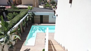 Ein Dachpool mit Holzterrasse und Topfpflanzen.