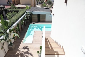 A rooftop swimming pool with a wooden deck and potted plants. - Vrbo Property (Lido Manfria)