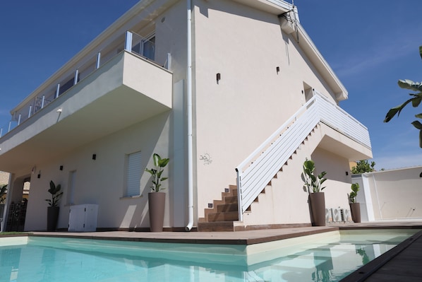 A two-story building with a swimming pool in the foreground. - Vrbo Property (Lido Manfria)