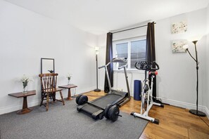 Un gimnasio en casa con cinta de correr, pesas y bicicleta estática.