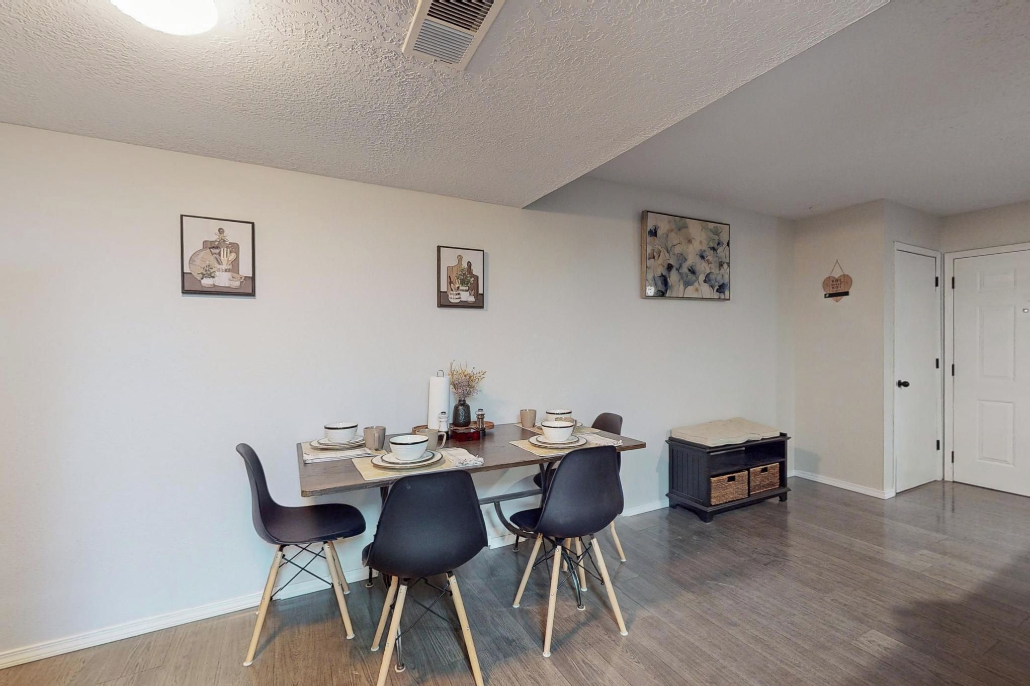 A dining area with a table set for four, chairs, and wall art.