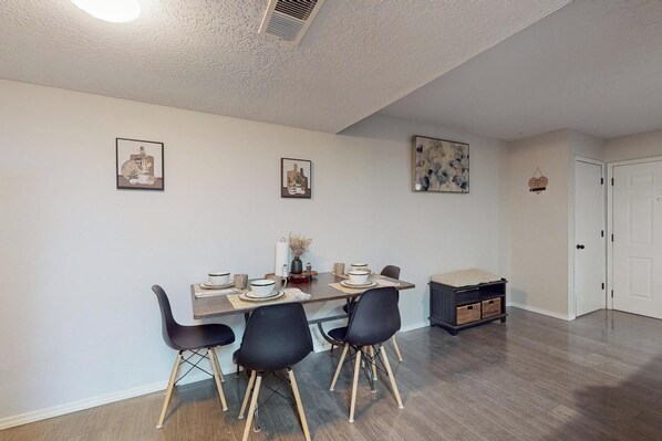 A dining area with a table set for four, chairs, and wall art.