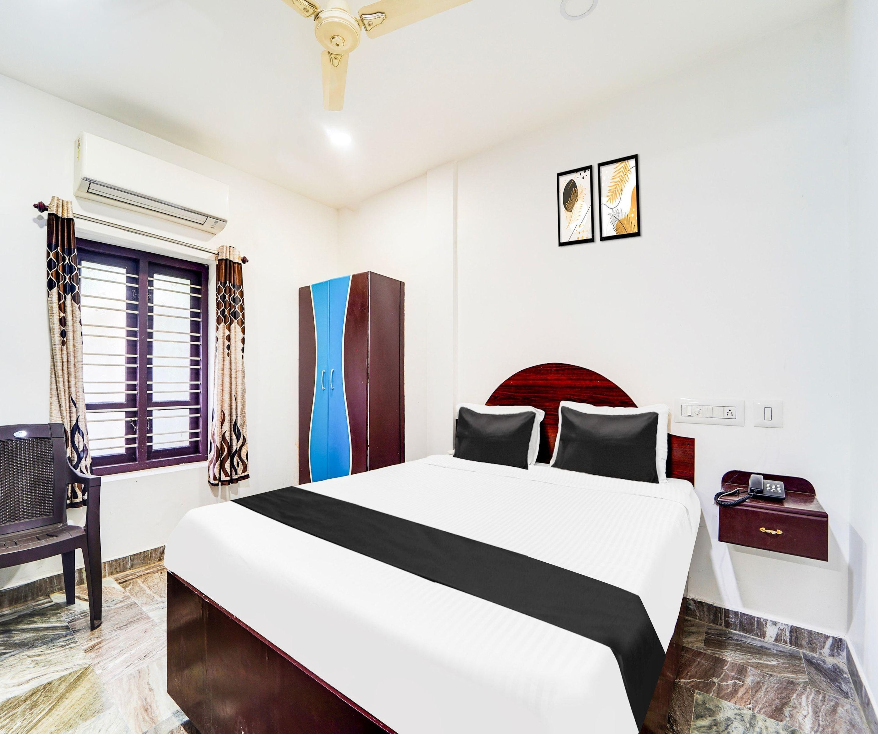 A hotel room with a bed, a desk, a chair, a wardrobe, and a telephone.