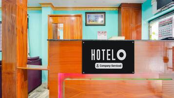 A hotel reception desk with a sign indicating it is company-serviced.