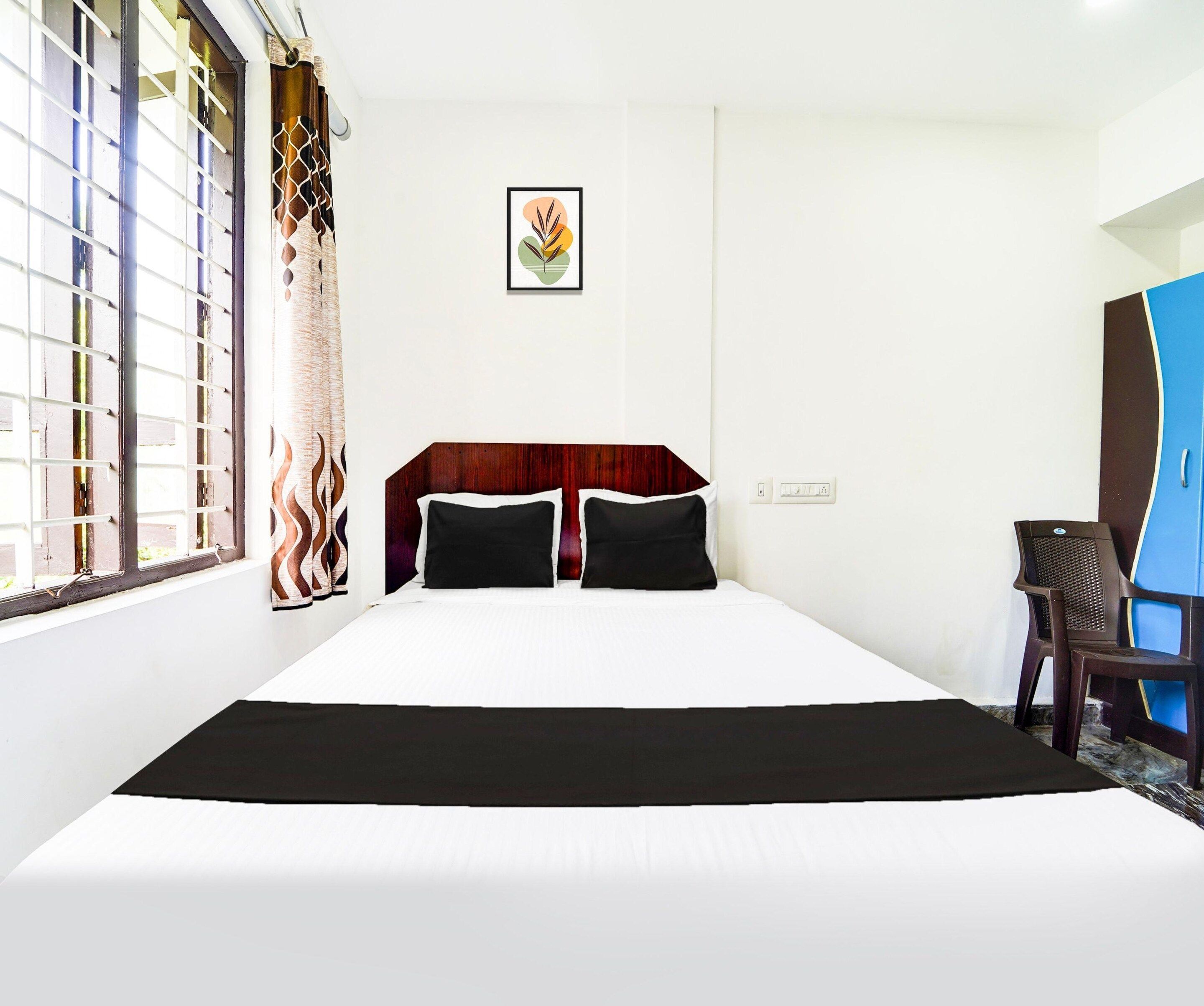 A hotel room with a bed, a desk, a chair, a window with a view, and a wall-mounted picture.
