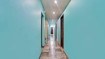 A corridor with teal walls and a marble floor leading to a door at the end.