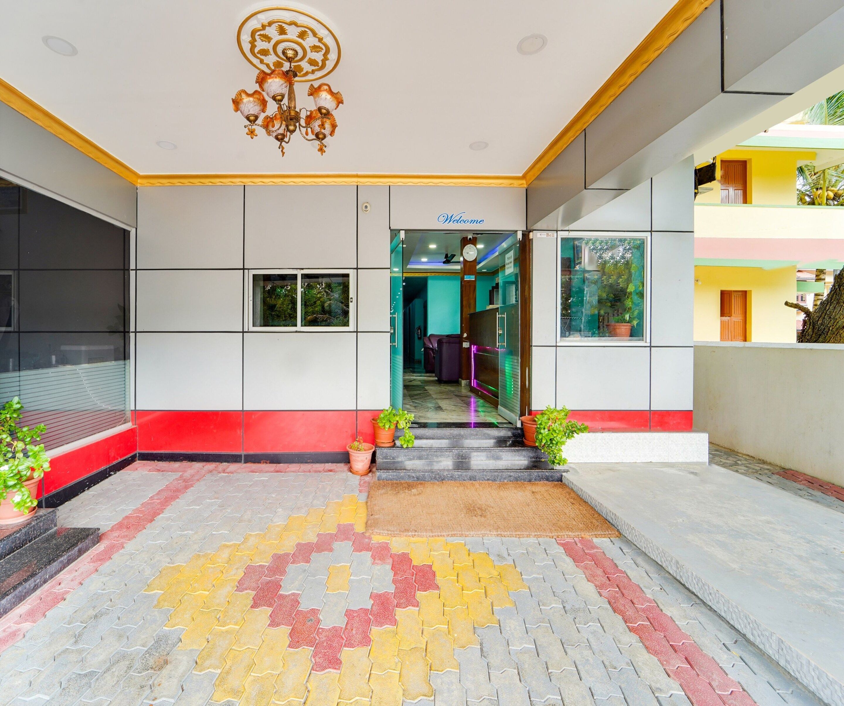 A hotel entrance with a tiled floor, a clock, and a welcome sign.