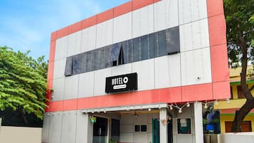 Un hotel de dos pisos con un letrero que indica que ofrece servicios para empresas. El edificio tiene techo plano y una decoración bicolor roja y blanca.