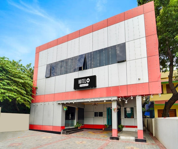 A two-story hotel with a sign indicating it is company-serviced. The building has a flat roof and a red and white color scheme. - Classic Hotel Jaisas Paradise (Nagercoil)