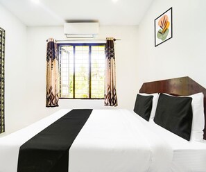 Habitación de hotel con cama, cortinas, ventana con vistas y aire acondicionado instalado en la pared.
