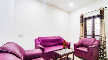 A room with two purple sofas, a small wooden coffee table, and a ceiling fan.