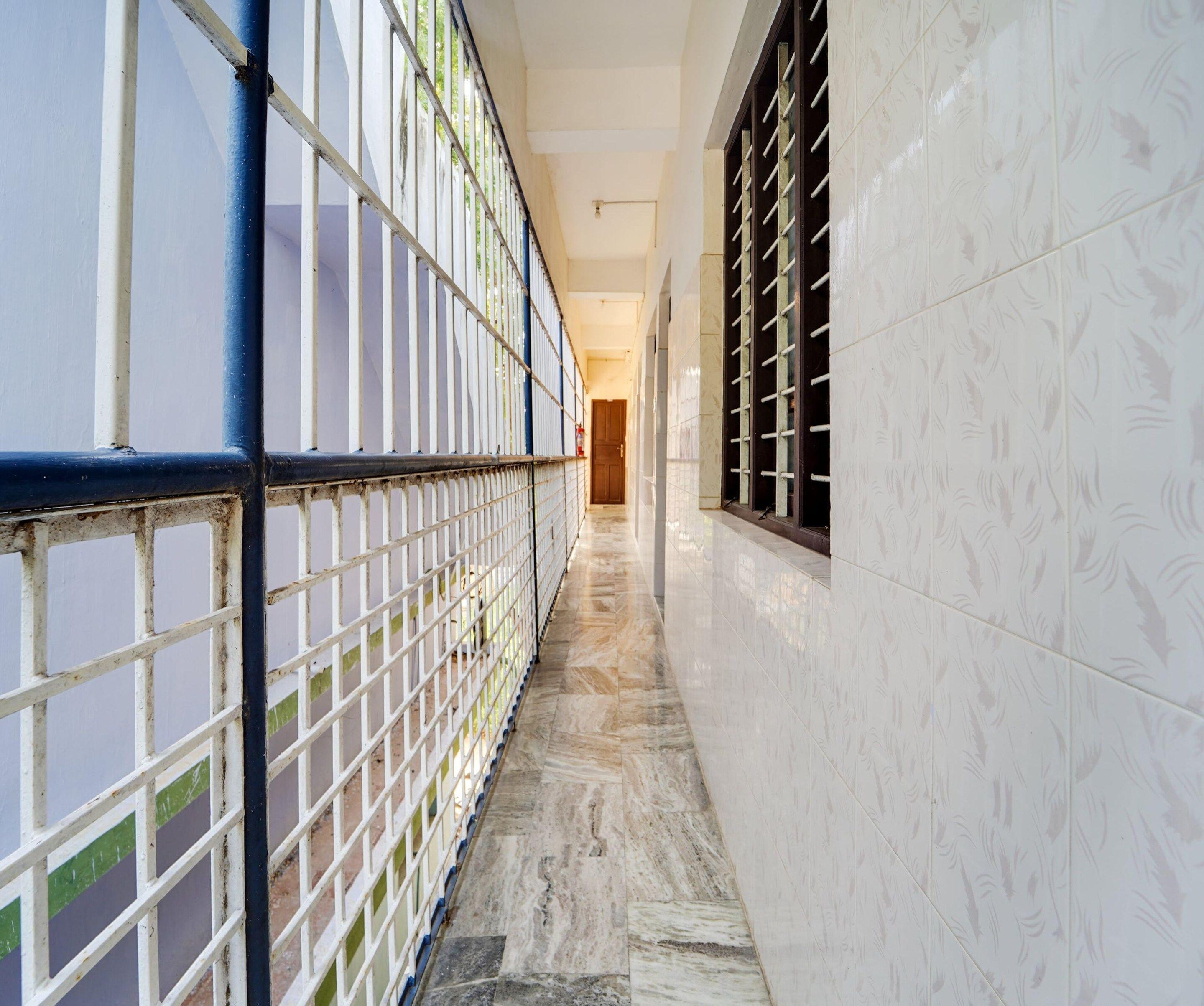 A corridor with tiled walls, a tiled floor, and metal railings on one side.