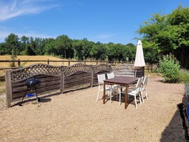 Un espacio al aire libre con un banco de madera, una mesa y sillas.