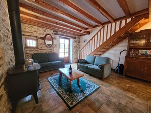 A cozy living room with a stone wall, a wooden staircase, a sofa, a coffee table, and a fireplace. - Authentic Estate in the Dordogne With a Pool (Saint-Saud-Lacoussiere)