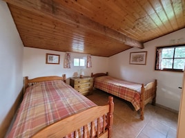 Una habitación con dos camas de madera, un aparador y una ventana con cortinas.