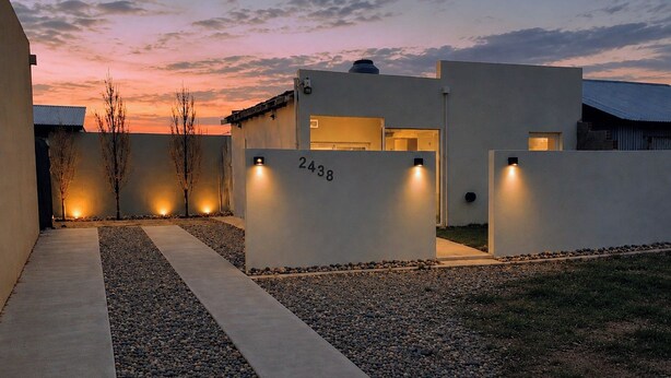 Een modern gebouw met een nummer, buitenverlichting en een grindpad.