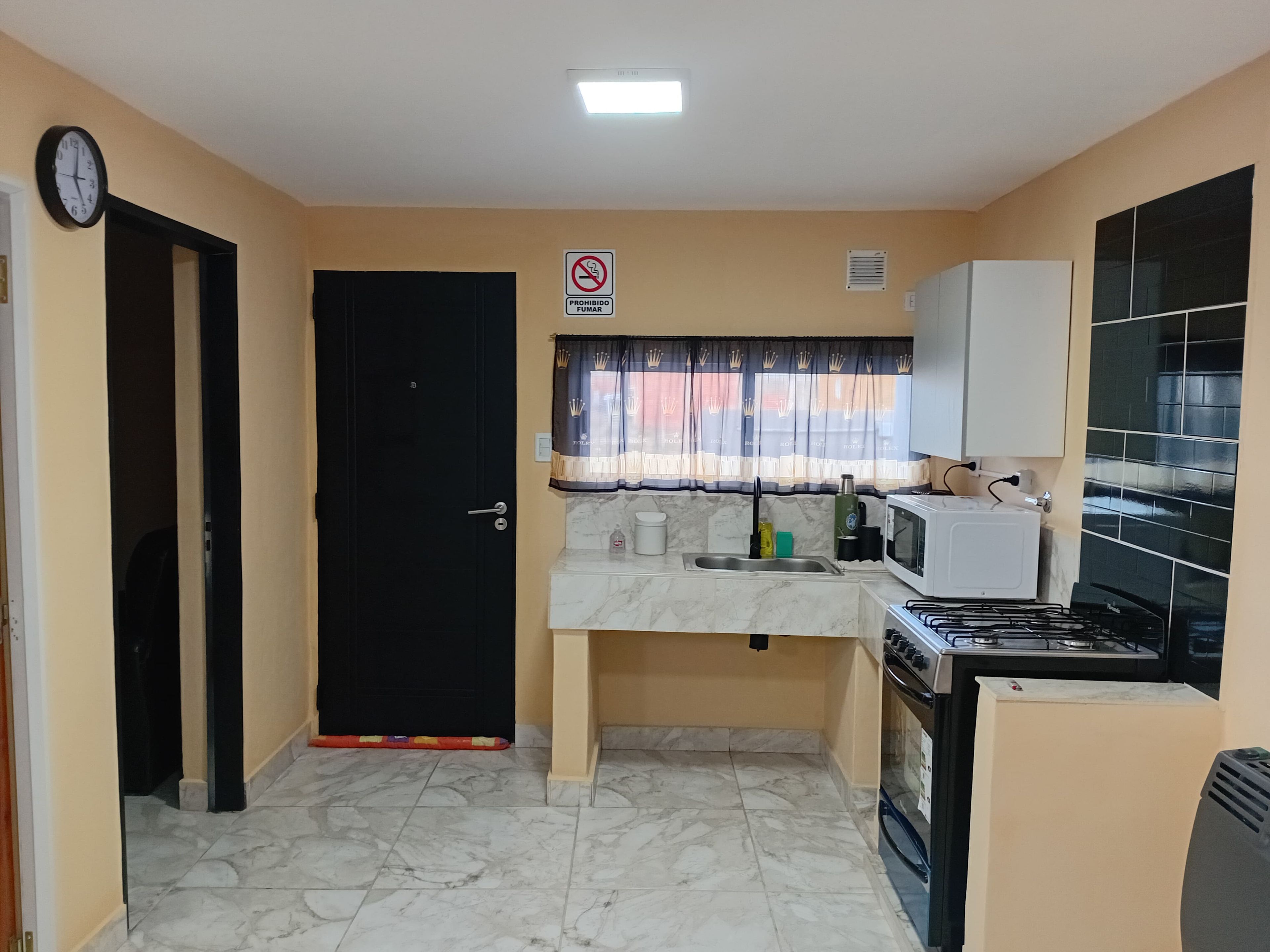 Una cocina compacta con una puerta negra, un microondas, una estufa y un lavaplatos.