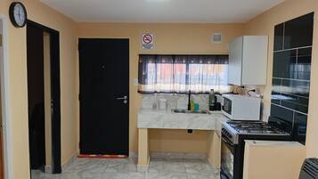 Una cocina compacta con una puerta negra, un microondas, una estufa y un lavaplatos.