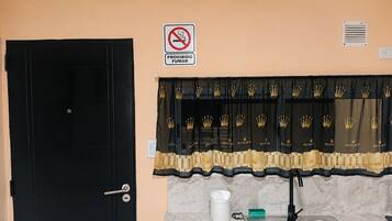 A kitchen with a sink, a door, and a sign prohibiting smoking.