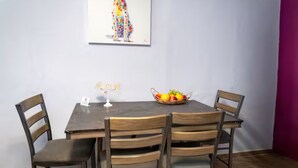 Ein Essbereich mit Holztisch und -stühlen, einem Obstkorb und einem Wandbild.