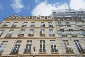 A multi-story building with a classic architectural style, featuring evenly spaced windows and decorative balconies. - Elegant Apartment With AC - Center of Paris (Paris)