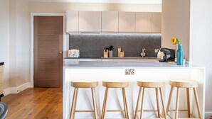 Une cuisine moderne avec un îlot central, des tabourets de bar et une porte en bois.