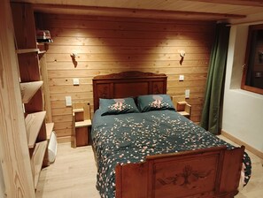 A wooden-paneled bedroom with a bed, a nightstand, and a shelf unit. - Menziesii Vacation Rental. In a traditional farmhouse just 5 minutes from the village center (Abondance)