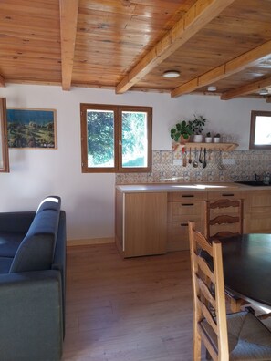 A modern kitchen with wooden cabinets, a dining table, and a sofa. - Menziesii Vacation Rental. In a traditional farmhouse just 5 minutes from the village center (Abondance)