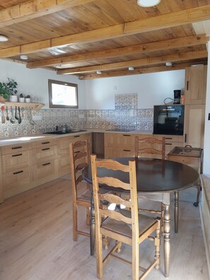 A kitchen with wooden cabinets, a dining table, and chairs. - Menziesii Vacation Rental. In a traditional farmhouse just 5 minutes from the village center (Abondance)
