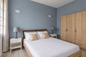 A bedroom with a bed, bedside tables, lamps, and a wardrobe. - Cozy Flat with Rooftop in the Heart of Valletta (Valletta)