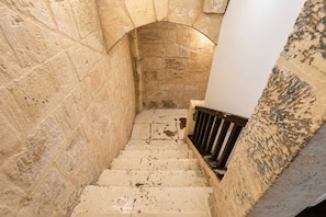 A narrow stone staircase with a metal handrail, leading to an arched doorway. - Cozy Flat with Rooftop in the Heart of Valletta (Valletta)