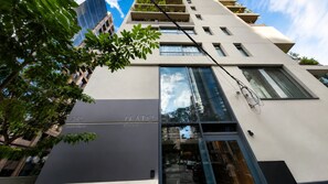 A modern building with a glass facade, balconies, and a clear sky. - Nato Itaim (São Paulo)