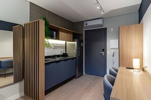 A modern kitchen with a built-in stove, a refrigerator, and a dining area with a table and chairs. - Nato Itaim (São Paulo)