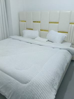 A bed with a white headboard and pillows, a white bedspread, and a white curtain. - Cozy 1-bedroom apartment in lovely Nanyuki with AC.Mt Kenya view, Olpejeta Conse (Nanyuki)