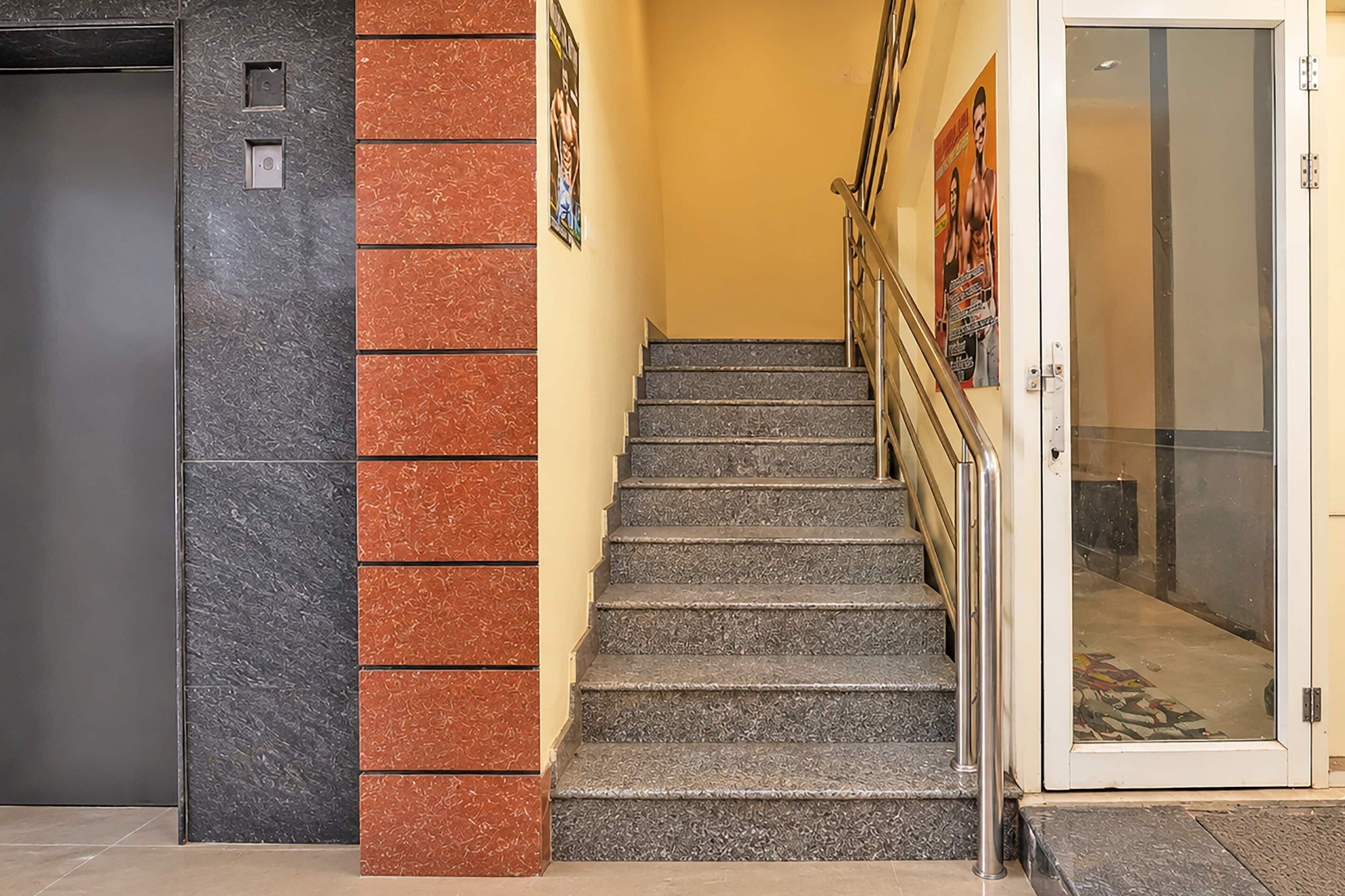 A staircase with a handrail, a door with a glass panel, and a wall with a textured pattern.