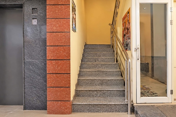 A staircase with a handrail, a door with a glass panel, and a wall with a textured pattern.