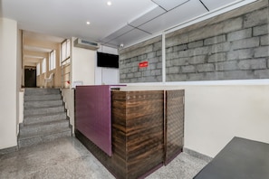 A reception area with a reception desk, a staircase, and a wall with a brick pattern.