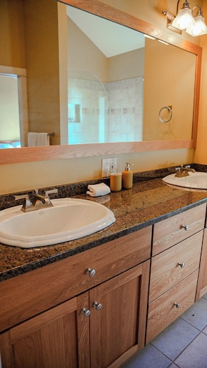 Un baño con dos lavamanos, un espejo grande, armarios de madera y un perchero para toallas.