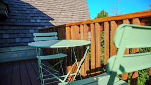 A wooden deck with a table and chairs, a brick wall, and a clear blue sky. - The Retreat - Luxury Mountain Home (Roseland)
