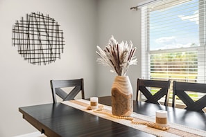 A dining table with a vase of dried plants, a candle, and a wooden tray. - Waterfront 4-bedroom luxury pool home (Winter Haven)