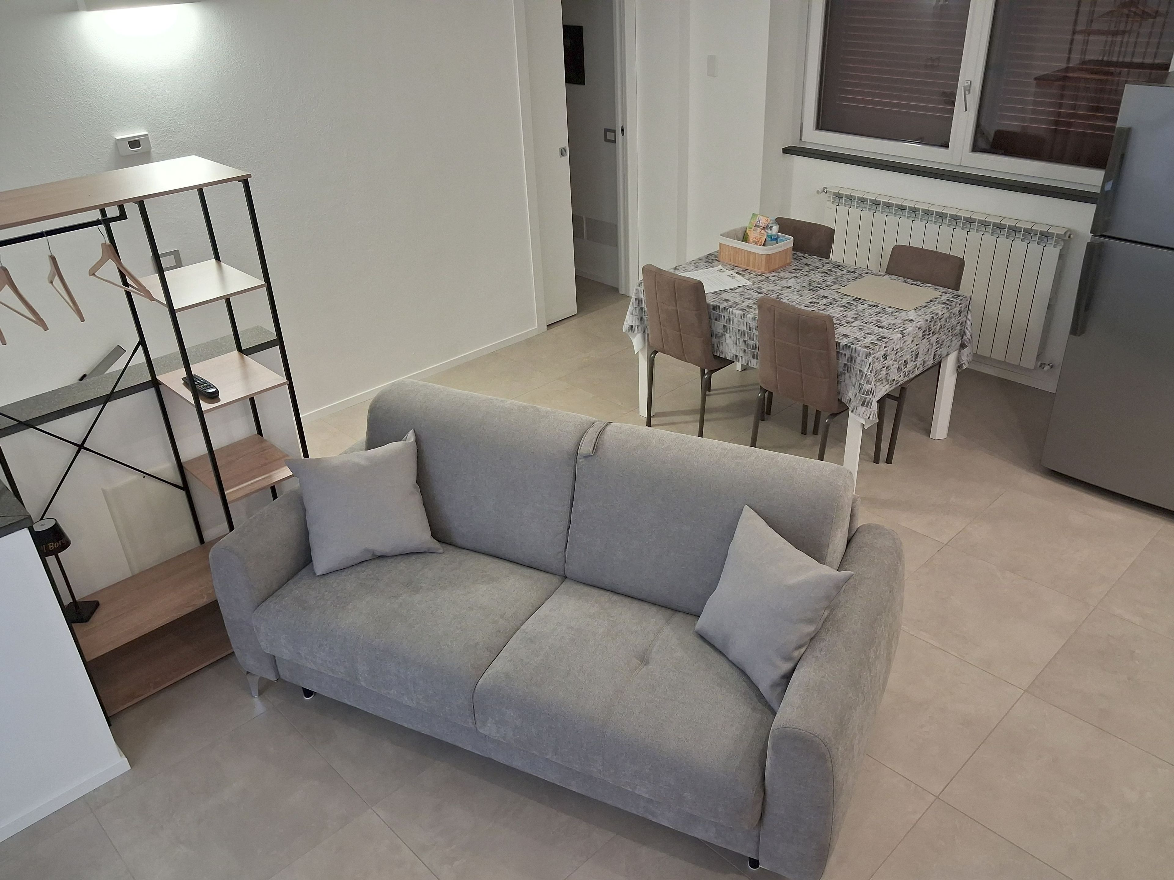 Ein Wohnzimmer mit grauem Sofa, einem kleinen Tisch mit Stühlen und einer Heizung.