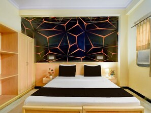A bedroom with a large bed, a wardrobe, a nightstand with a lamp, and a decorative wall panel. - Collection O Albert Hall Museum Jaipur (Jaipur)