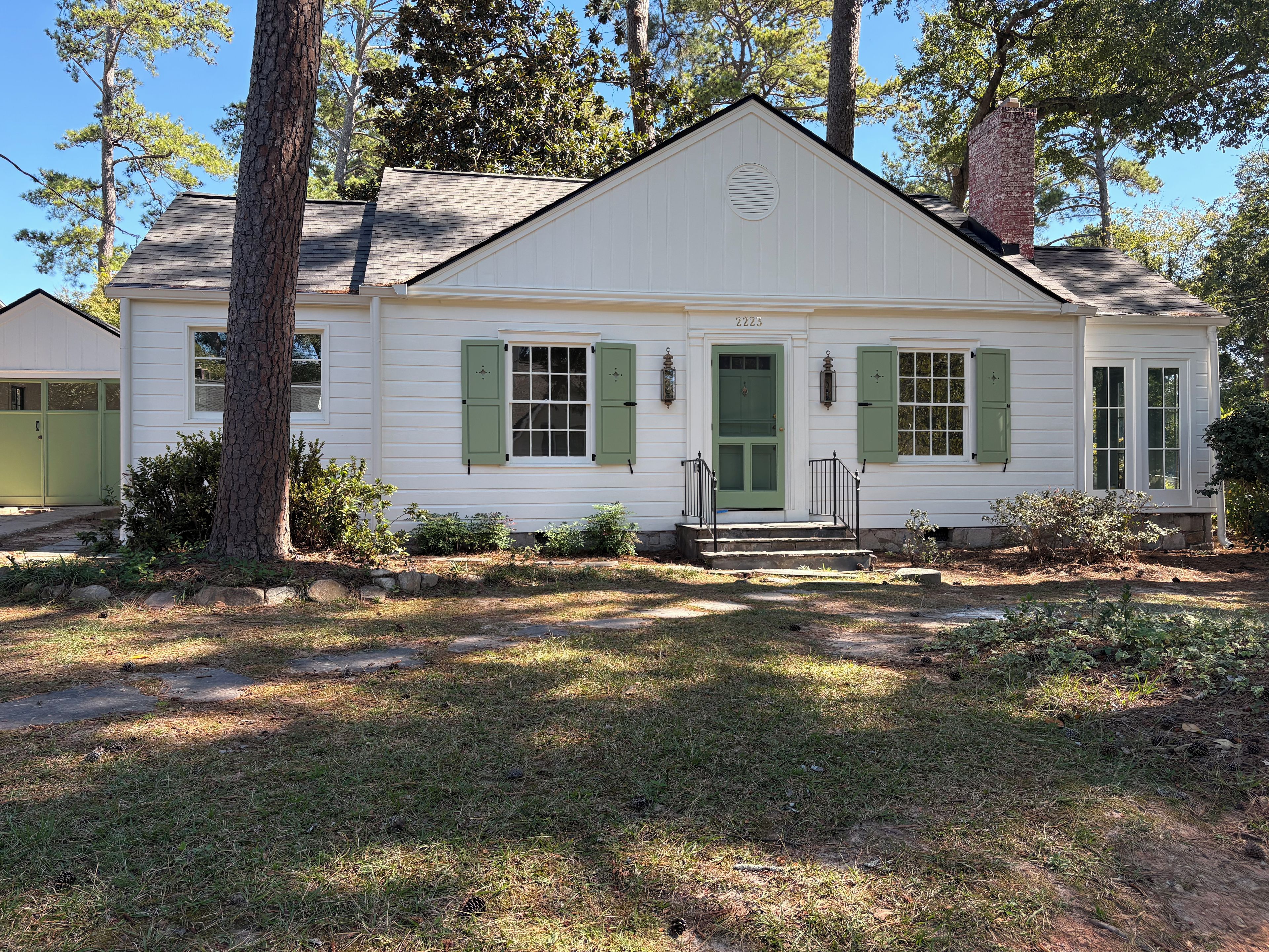 A single-story house with a front porch, a green door, and a number '2223' on the front wall.