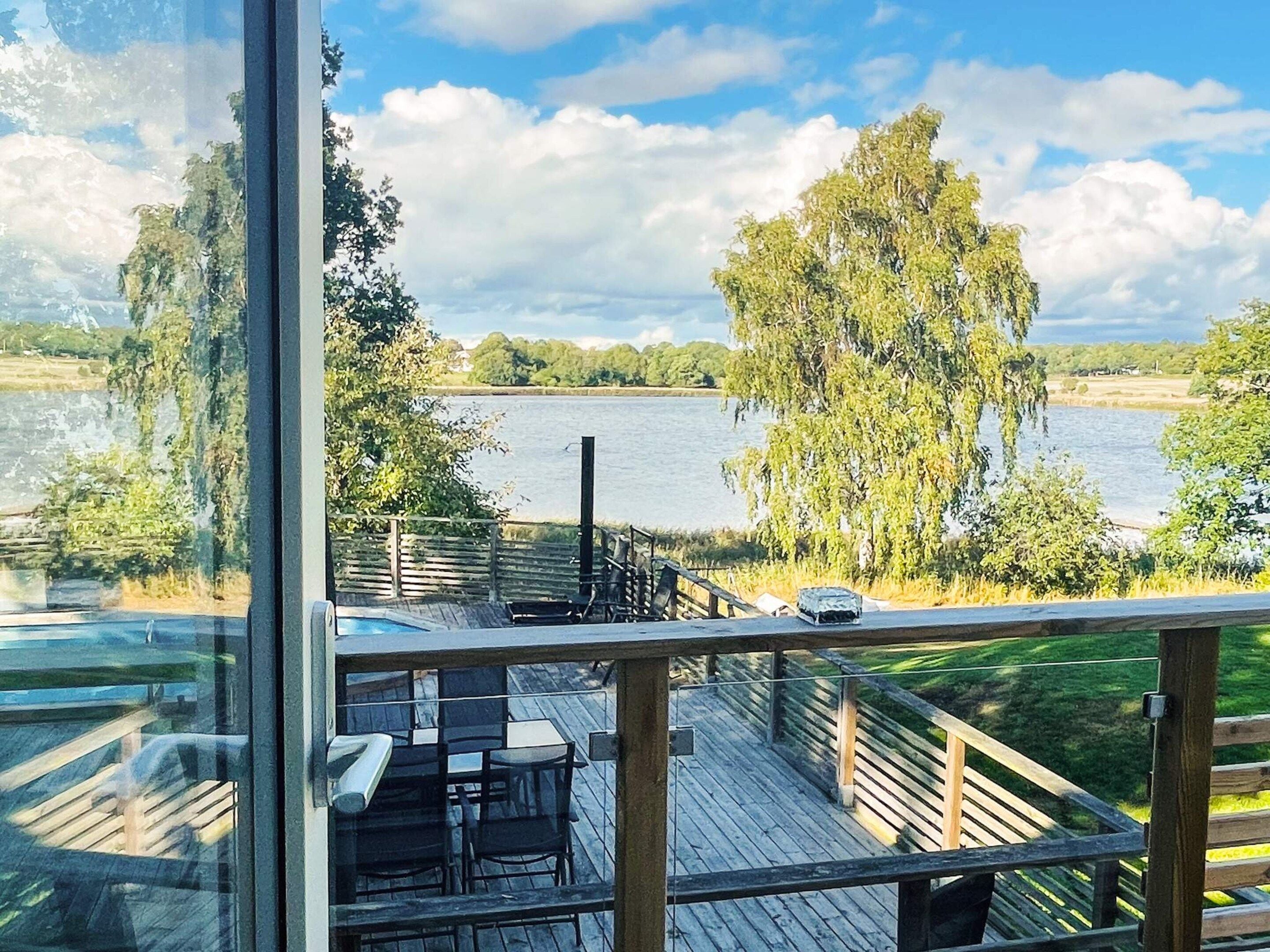 Une terrasse en bois avec des sièges extérieurs donnant sur un lac.