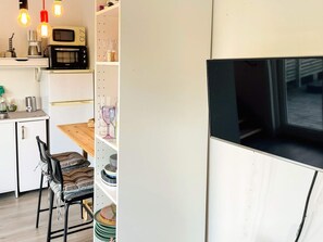 Cozinha compacta com micro-ondas, cafeteira e uma pequena mesa de jantar com uma cadeira.