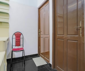 Un pasillo con una silla, un juego de puertas dobles y una escalera.
