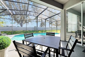 Un espacio al aire libre techado con piscina, mobiliario y vistas del paisaje circundante.