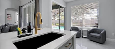 A modern kitchen with a large island, a built-in oven, and a view of a pool.