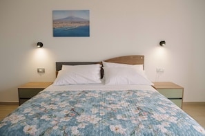 A bedroom with a bed, two bedside tables, a nightstand, a wall-mounted lamp, and a painting of a landscape. - Aetnamare: A 360° View (Mascalucia)
