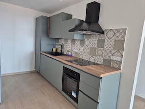 A modern kitchen with a built-in oven, a black range hood, and a patterned backsplash. - Aetnamare: A 360° View (Mascalucia)